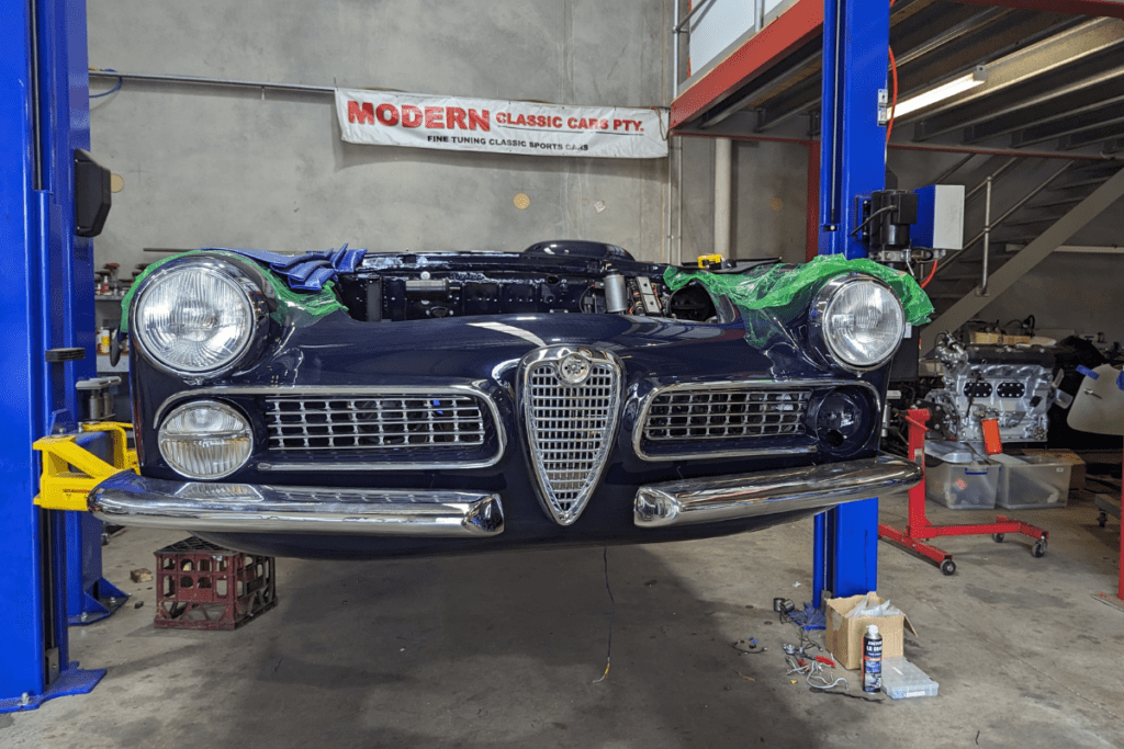 Alfa Touring 2000 on hoist during restoration process